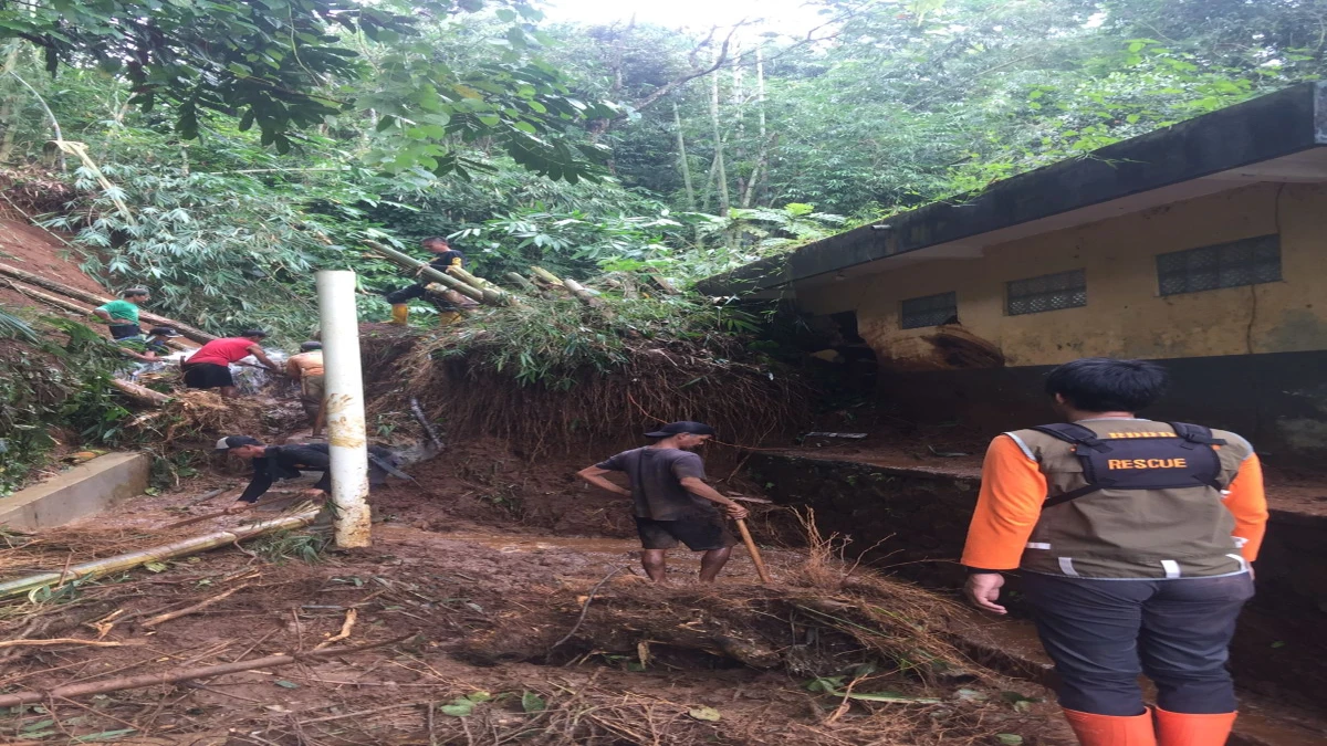 Petugas BPBD dan warga membersihkan material longsor yang menimpa pemandian umum di Kampung Cigoleup, Desa Sindanglaya, Kecamatan Tanjungsiang, pada Minggu (16/3/2025).